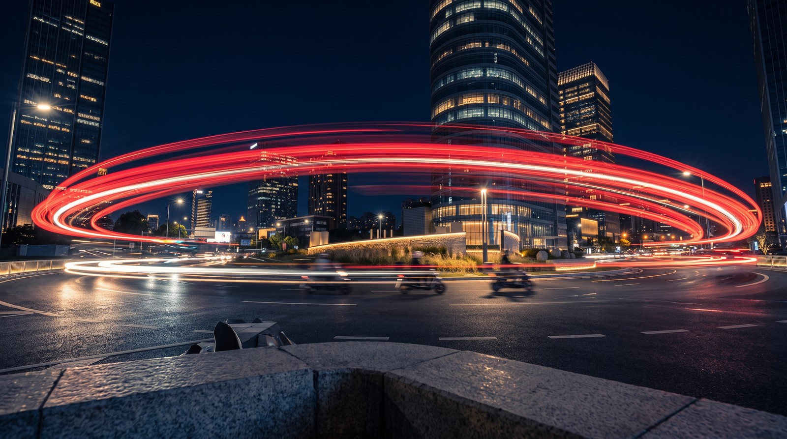 Traînées lumineuses de véhicules autour d'un rond-point urbain de nuit